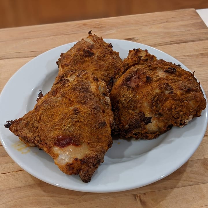 A nice plate of 3 delicious Air Fried Chicken thighs on a plate waiting to be eaten.