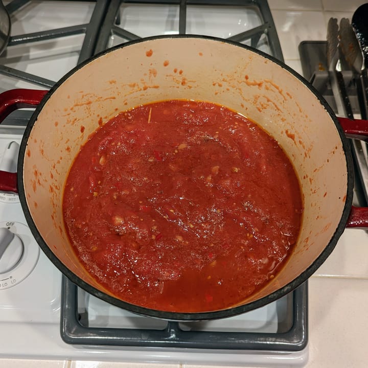 A very good looking marinara sauce simmering in a dutch oven.